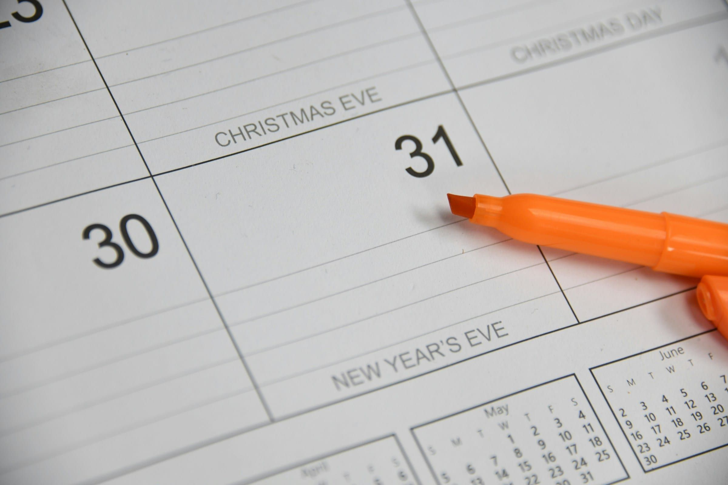 Close-up of a desk calendar with an orange highlighter resting on the last days of December