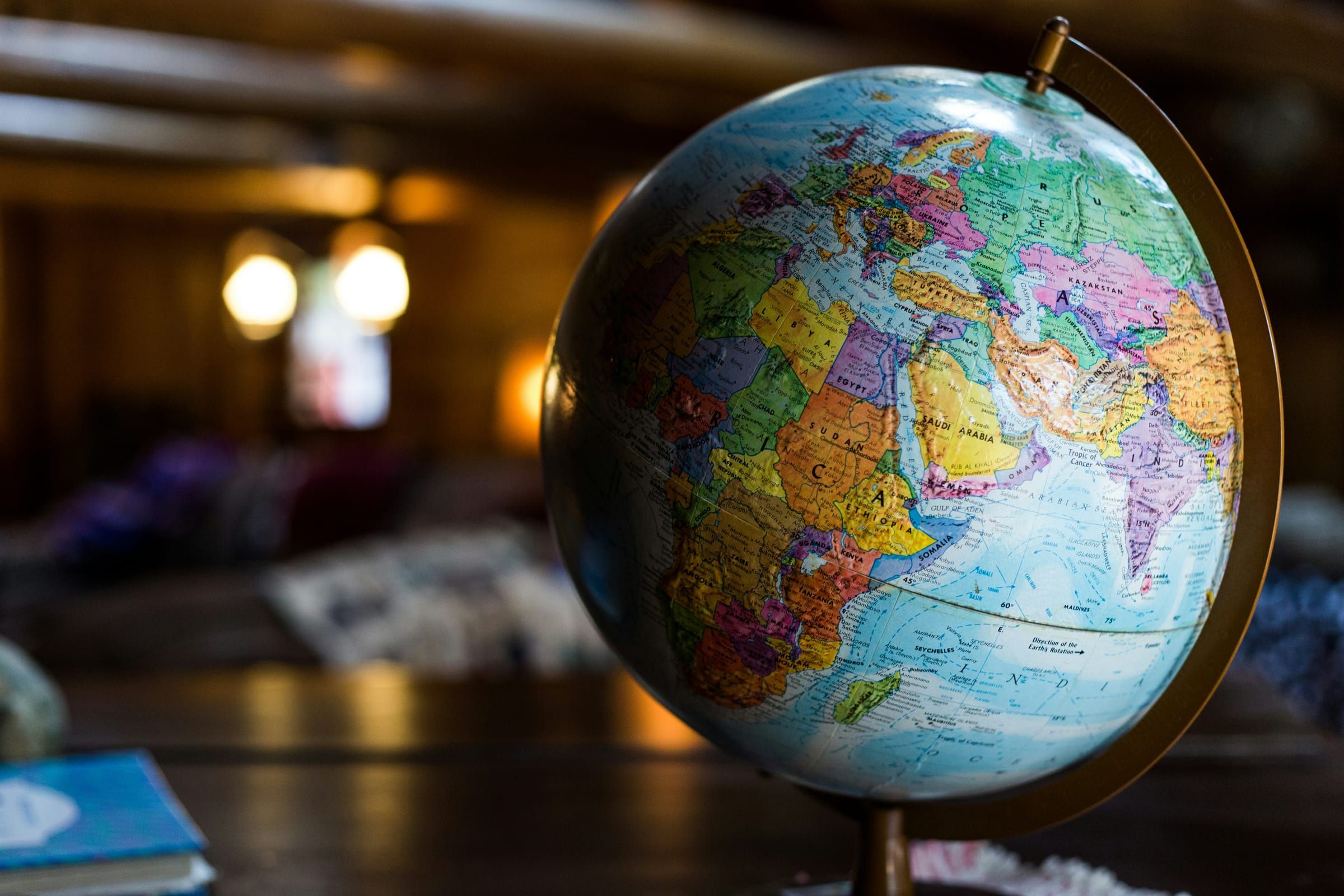 Um globo terrestre mostrando Europa, África e Ásia sobre uma mesa de madeira escura em uma sala com luz quente