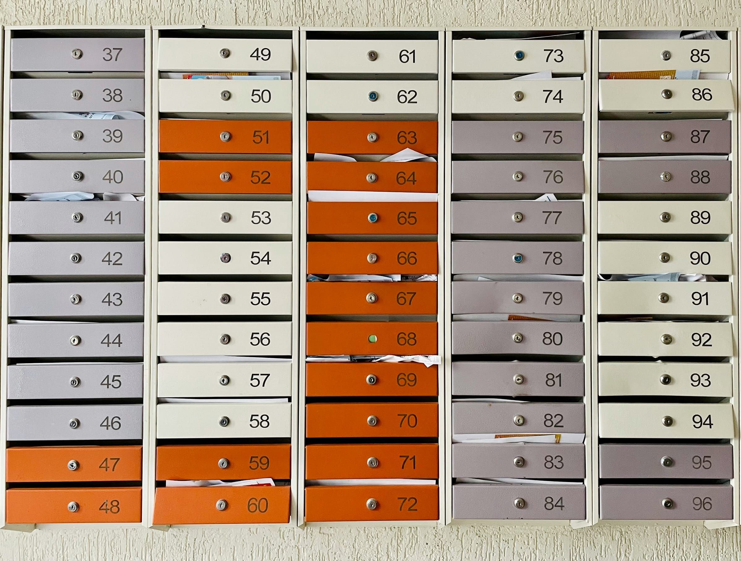 Fileiras de caixas de correio numeradas com portas laranja e cinza